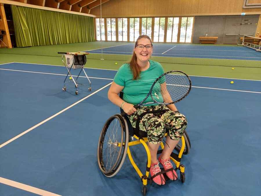 Dunna en ina sutga cun rodas da tennis en ina halla interna.
